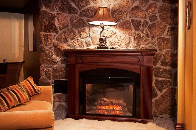 Electric fireplace and stone wall in the Golden Oaks corner suite